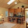 Mudroom opens to a large room with vaulted ceiling.  Living, dining and kitchen are combined as in a vacation house.  Island became the "hearth," the focal point that draws people in. Hall leads to a bedroom and bath, and includes alcoves for study and laundry.   