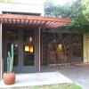 East entry to addition from garden has a pergola hovering over French doors.