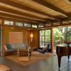 New living room with exposed beams has transoms in between. Continuous soffit sets height for doors and alcove. Shoji-like sliding glass doors open to a covered terrace. 